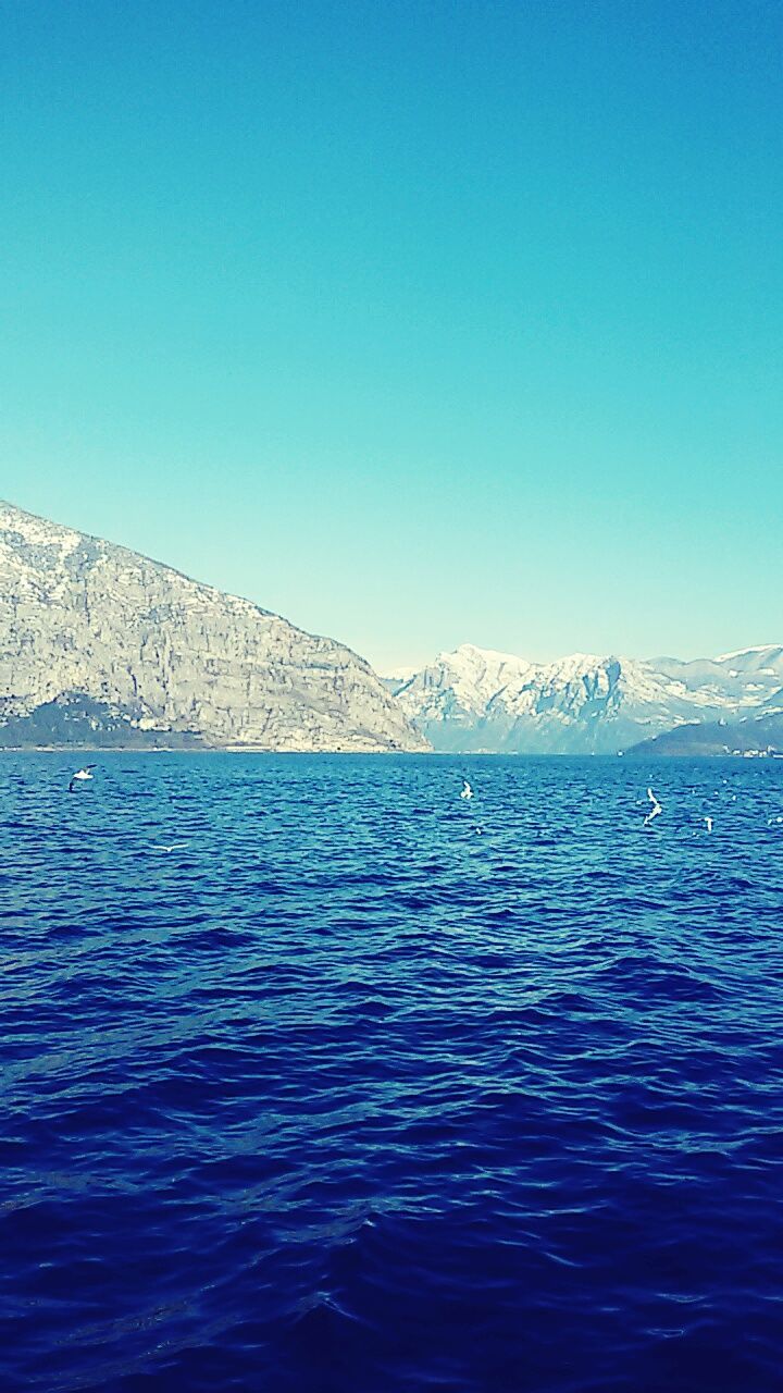 blue, clear sky, water, waterfront, copy space, sea, scenics, tranquil scene, beauty in nature, tranquility, rippled, nature, mountain, idyllic, day, outdoors, no people, remote, non-urban scene, lake