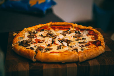 Selective focus of italian pizza, spices in grinders, bottle and glass of wine on wooden tabletop