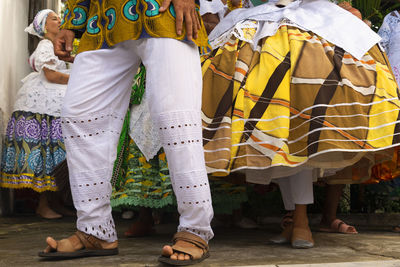 Lower part of candomble members dressed in traditional clothes for religious festival 