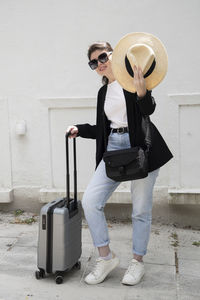 Young brunette girl in glasses with a suitcase goes on vacation,