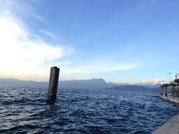 Wooden posts in sea against sky