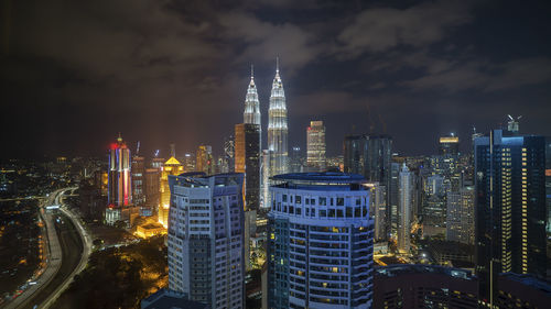 Illuminated buildings in city against sky at night