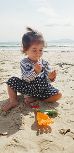 Portrait of boy sitting at sandy beach