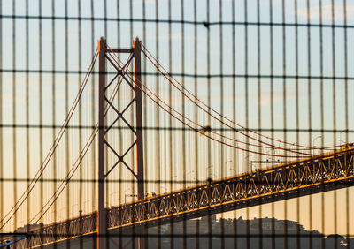 Low angle view of 25 de abril bridge against sky during sunset