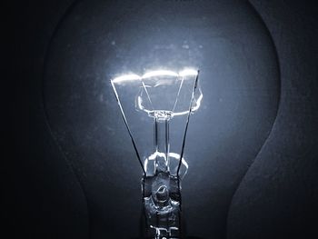 Low angle view of illuminated light bulb hanging at night