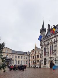 People in front of historic building against sky