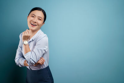 Smiling young woman against blue background