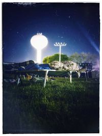 Digital composite image of illuminated lights on field against sky at night