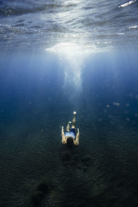 Shirtless young man diving over ocean floor underwater