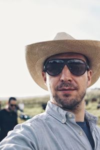 Portrait of mid adult man wearing sunglasses and straw hat while standing at field