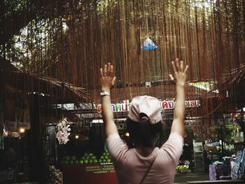 Rear view of woman with arms raised in city