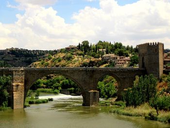 Arch bridge over river against sky