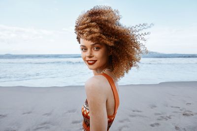 Portrait of young woman standing at beach