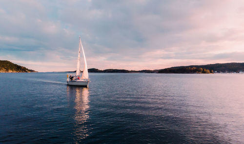 Sailboat sailing on sea against sky during sunset