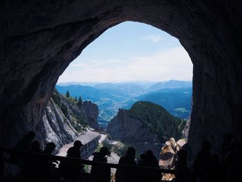 People seen through arch against mountains
