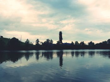 Silhouette trees by lake against sky during sunset