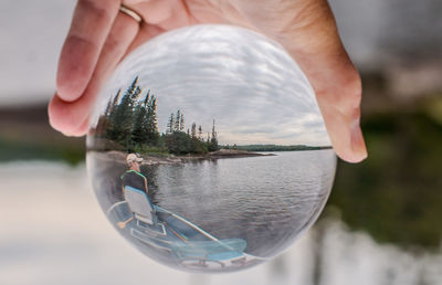 Close-up of hand holding crystal ball with reflection in water