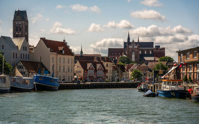 Boats in river against buildings in city