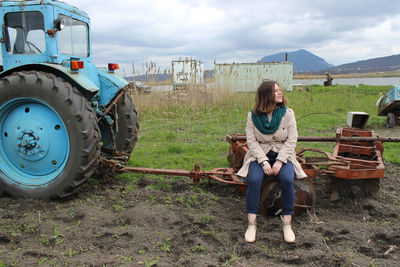Full length portrait of teenage girl sitting on field