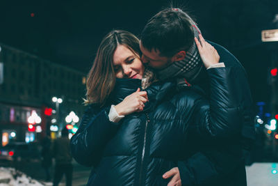 Young couple standing on street at night