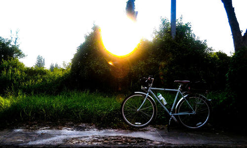 Bicycle on field against sky during sunset