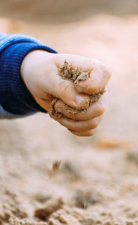 Cropped hand of man holding sand