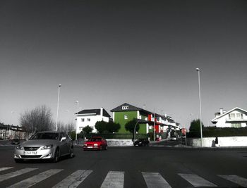 Cars on street by buildings against clear sky