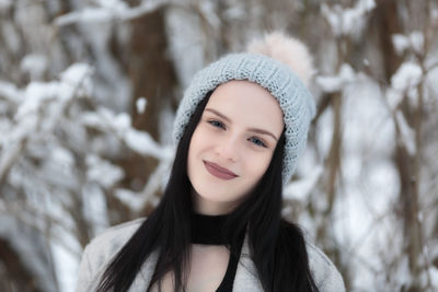 Portrait of smiling young woman standing in snow