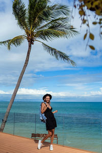 Rear view of woman standing at beach against sky