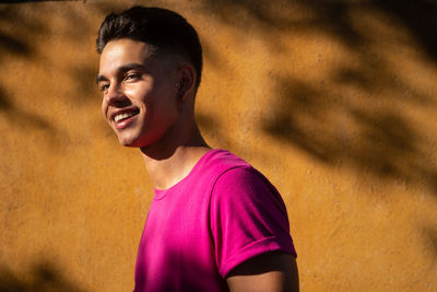 Portrait of smiling young man standing against wall