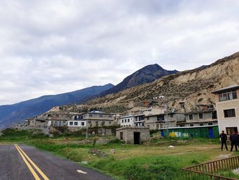 Road by buildings in city against sky