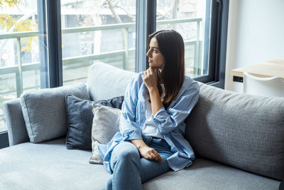 Young woman using laptop while sitting on sofa at home