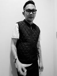 Portrait of young man wearing sunglasses standing against white background