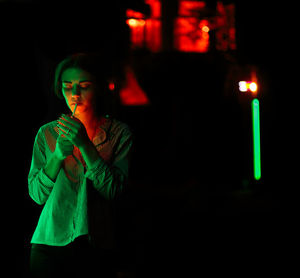 Portrait of young woman standing in city at night