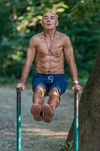 Portrait of shirtless man exercising in park