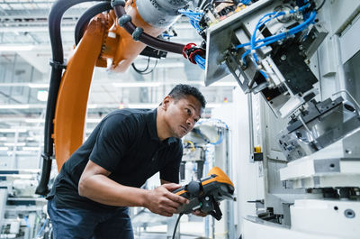 Engineer operating robotic arm at electrical industry