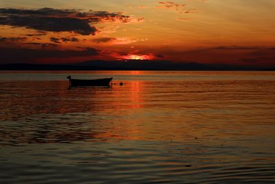 Silhouette boat in sea against sky during sunset