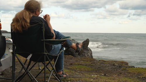 Rear view of woman sitting on beach