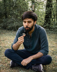 Young man eating while sitting on land