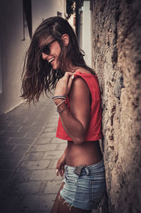 Portrait of smiling woman standing against wall