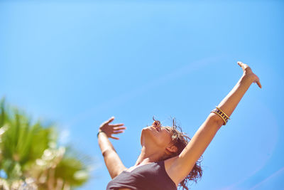 Low angle view of woman against clear blue sky