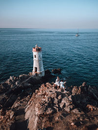 Lighthouse by sea against clear sky