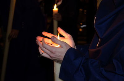 Midsection of man holding lit candles