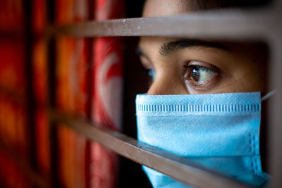 Close-up of woman wearing mask looking through window