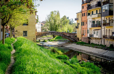 Arch bridge over canal amidst buildings against sky