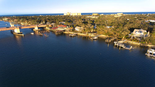Aerial view of illuminated city by sea against sky