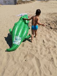 Full length of shirtless boy on sand at beach