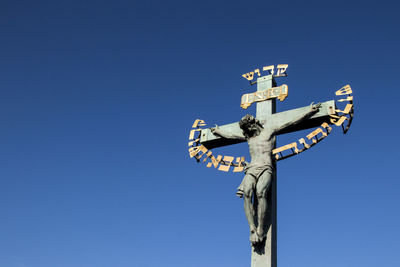 Low angle view of sign on pole against clear blue sky