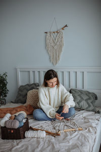 Young girl weaves using macrame technique at home