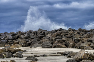 Sea waves splashing on rocks against sky